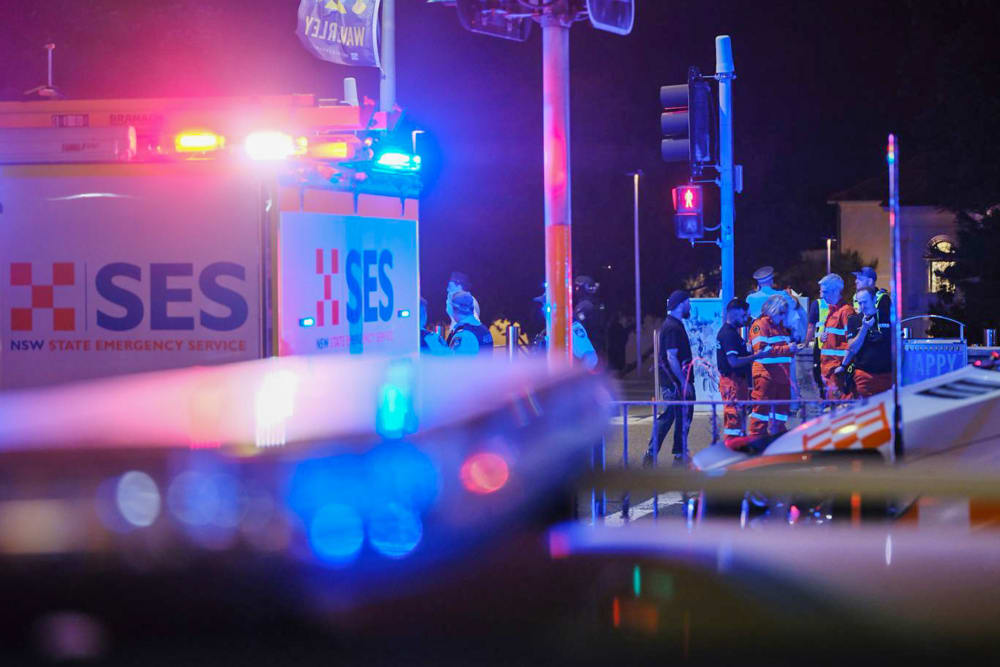 Emergency responders at Sydney's Bondi Beach in Australia confer amid the flashing lights of EMS vehicles.