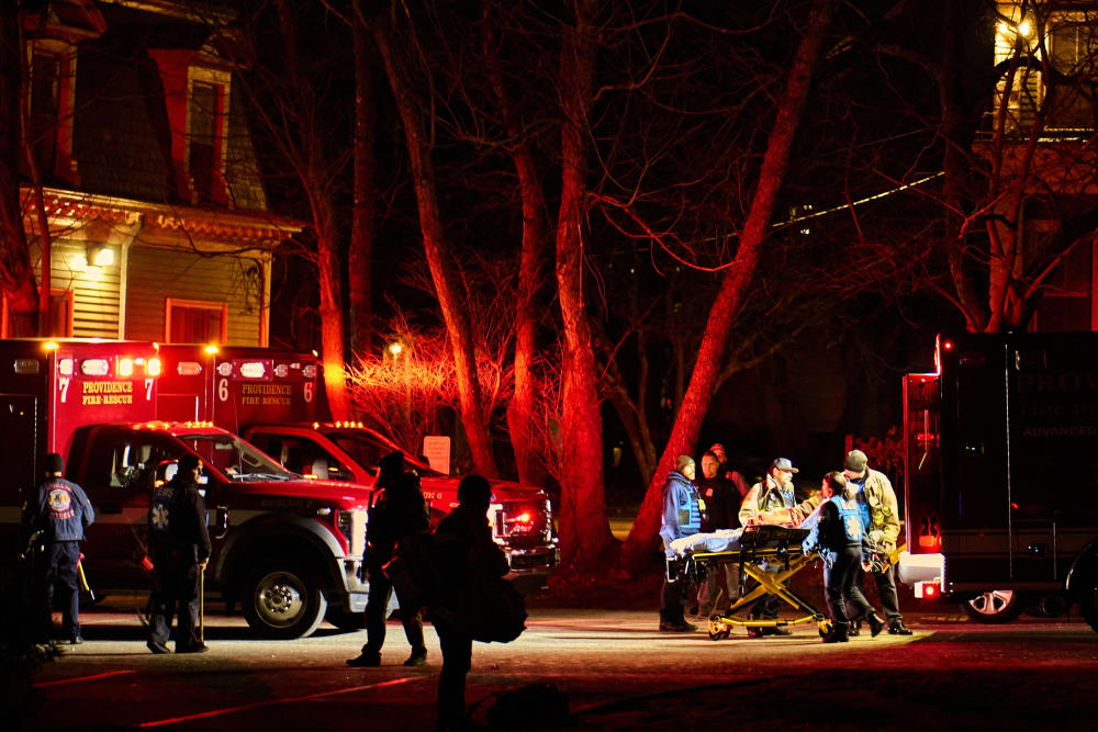 First responders wheel an empty gurney into an ambulance on Brown University campus.