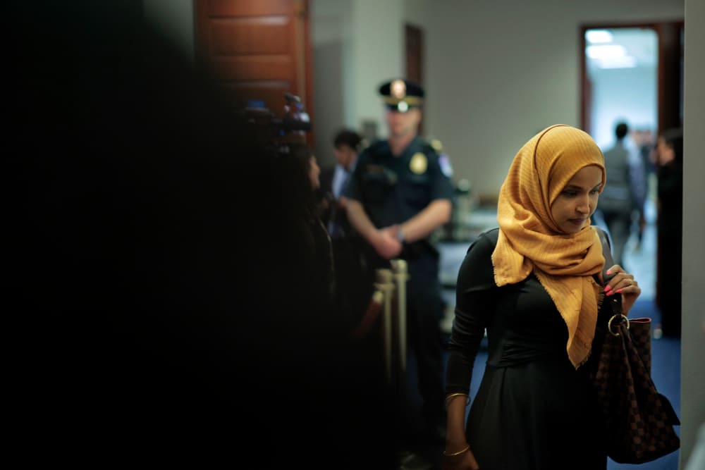 Rep. Ilhan Omar at the Capitol, with a police officer in the background.