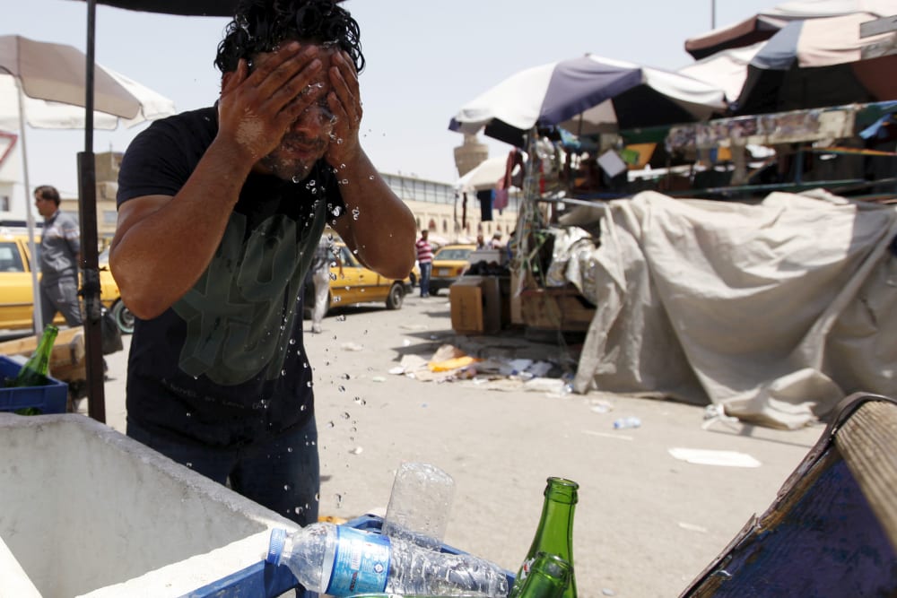 A man washes his face to cool off during a warm summer day in Baghdad (Photo by Ahmed Saad/Reuters).