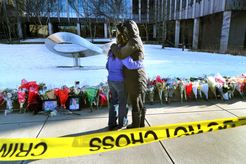 People hug in front of a memorial at Brown University.