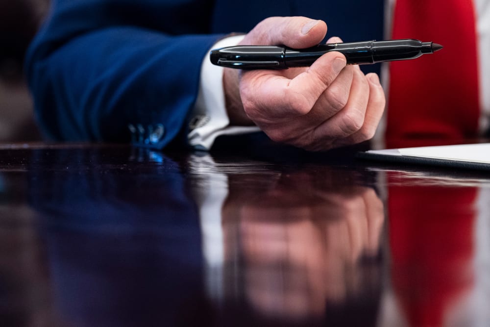 A close up of President Donald Trump's hand holding a pen.
