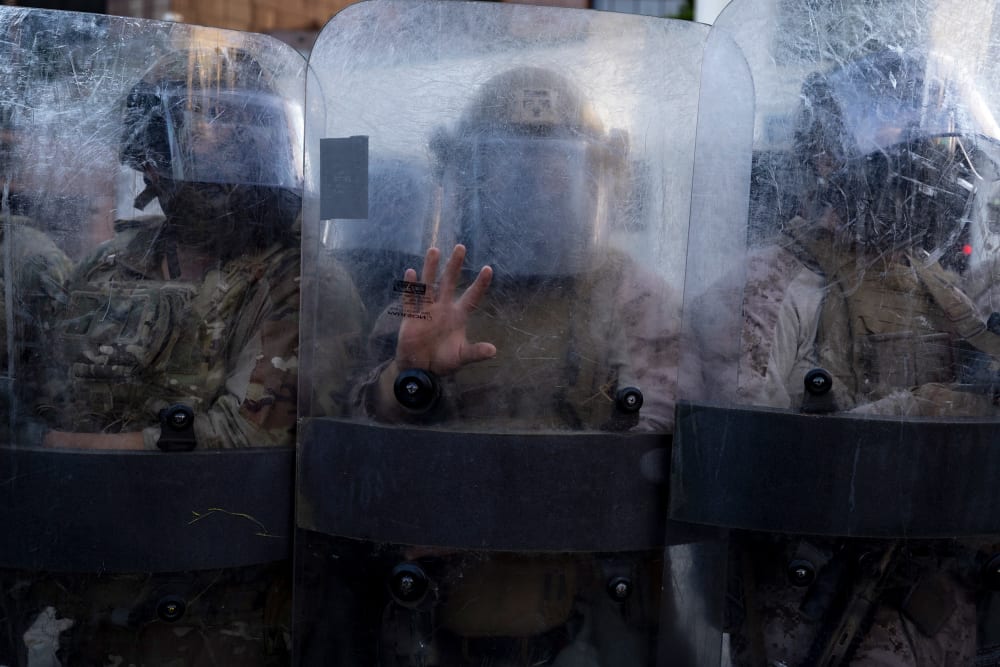 Members of the National Guard and Marines stand behind opaque shields.
