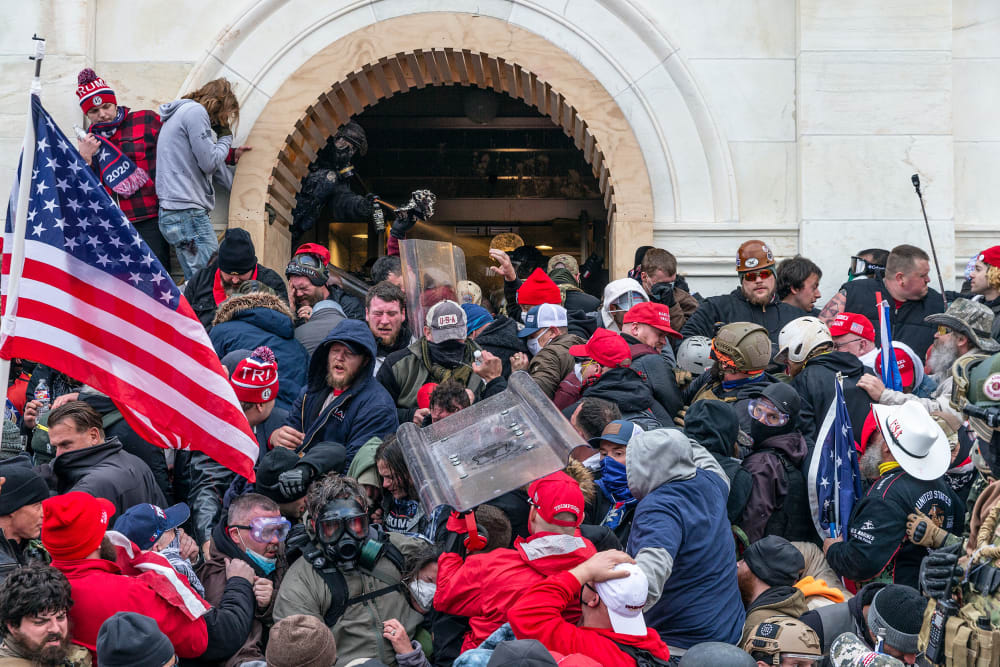 A police office sprays tear gas on a crowd of pro-Trump supporters attempting to enter the Capitol.
