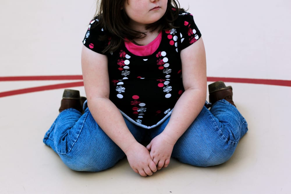 A child sits on the gym floor during the Shapedown program for overweight adolescents in Aurora, Colorado.