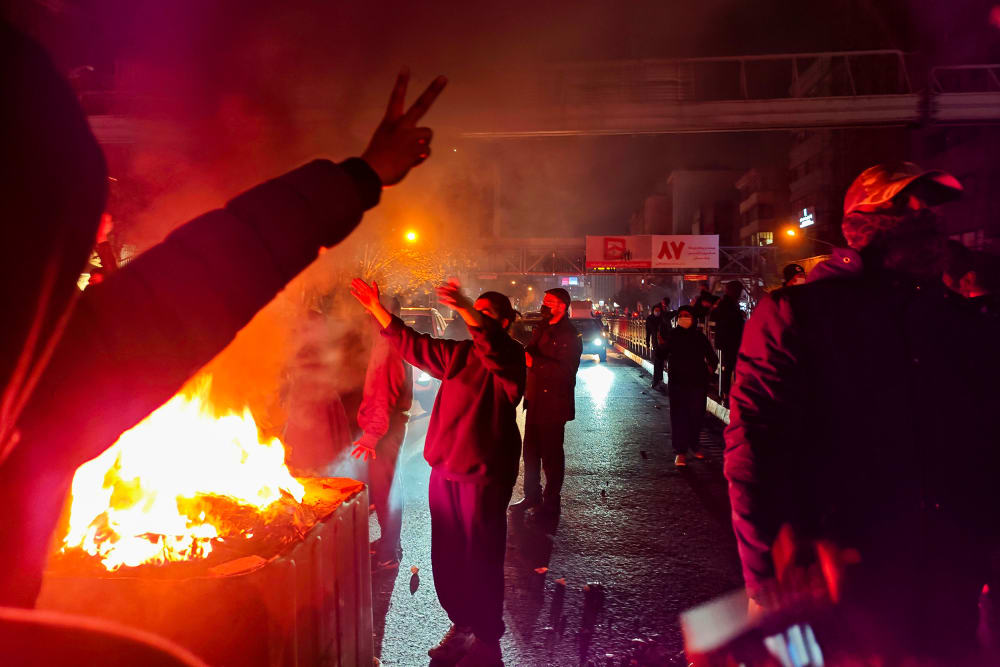 People gather around a fire lit on the streets of Tehran, Iran.