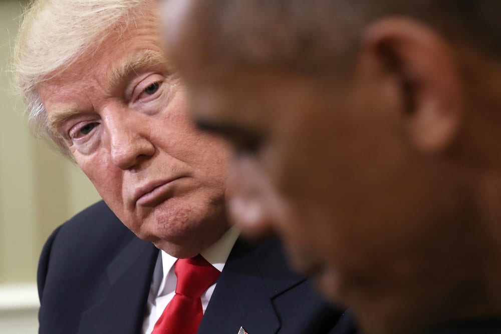 Donald Trump, in focus on the left, looks at Barack Obama, who is out of focus in the foreground.