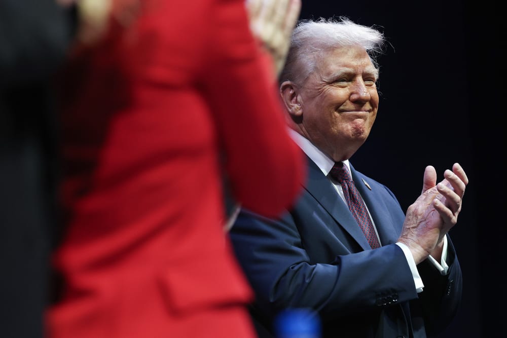 Donald Trump claps with a smile on his face.