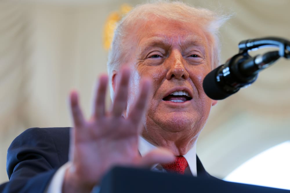 Donald Trump gestures with his hand in front of a microphone.