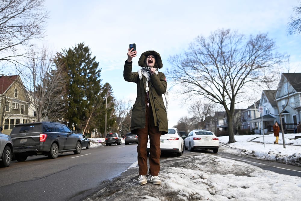 A person yells while holding up a cell phone.