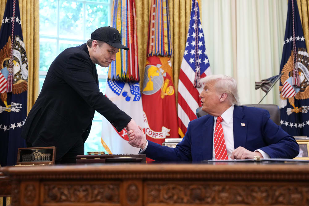 Elon Musk, left, and President Donald Trump shake hands in the Oval Office