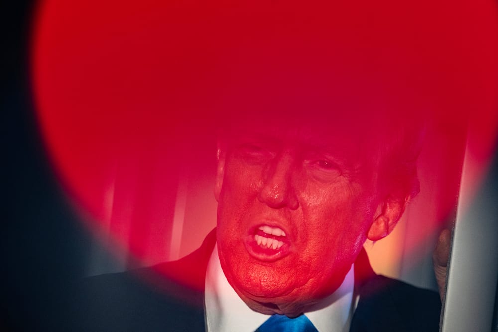 Top part of Donald Trump's face is seen through a round red light.