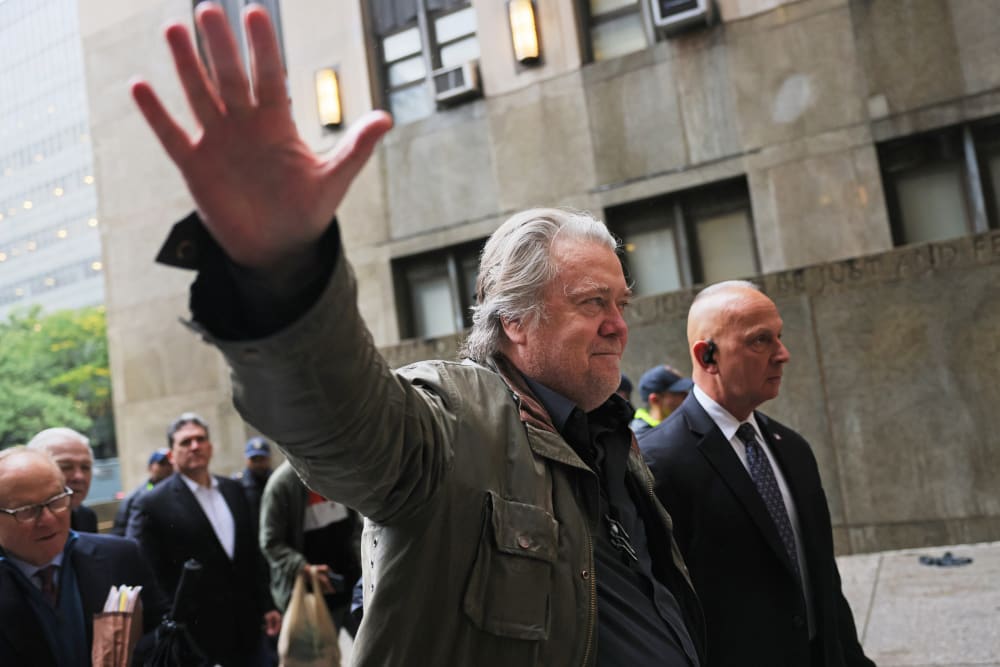 Steve Bannon waves his hand while walking into the court building.