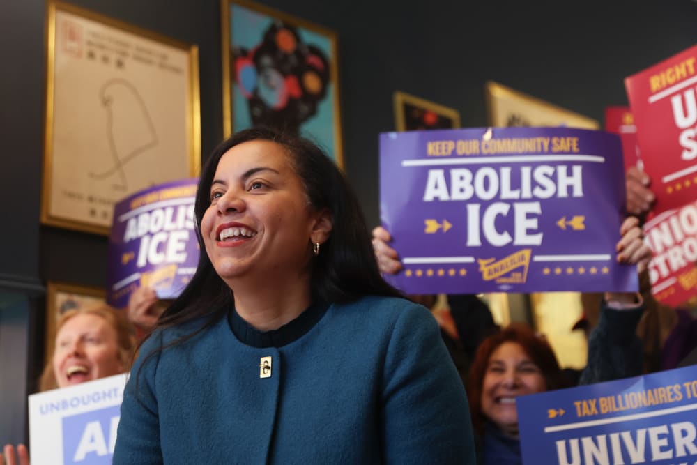 Analilia Mejia. People behind her hold signs in support.