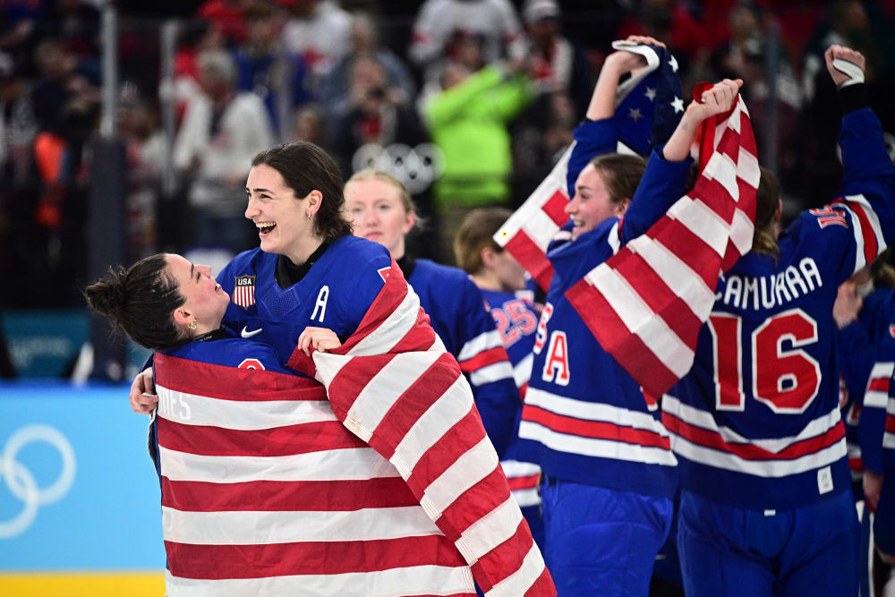 Hockey players in jerseys that read "USA" celebrate with American flags.
