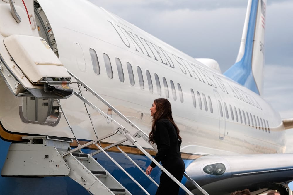 Kristi Noem walks the steps up into a plane.