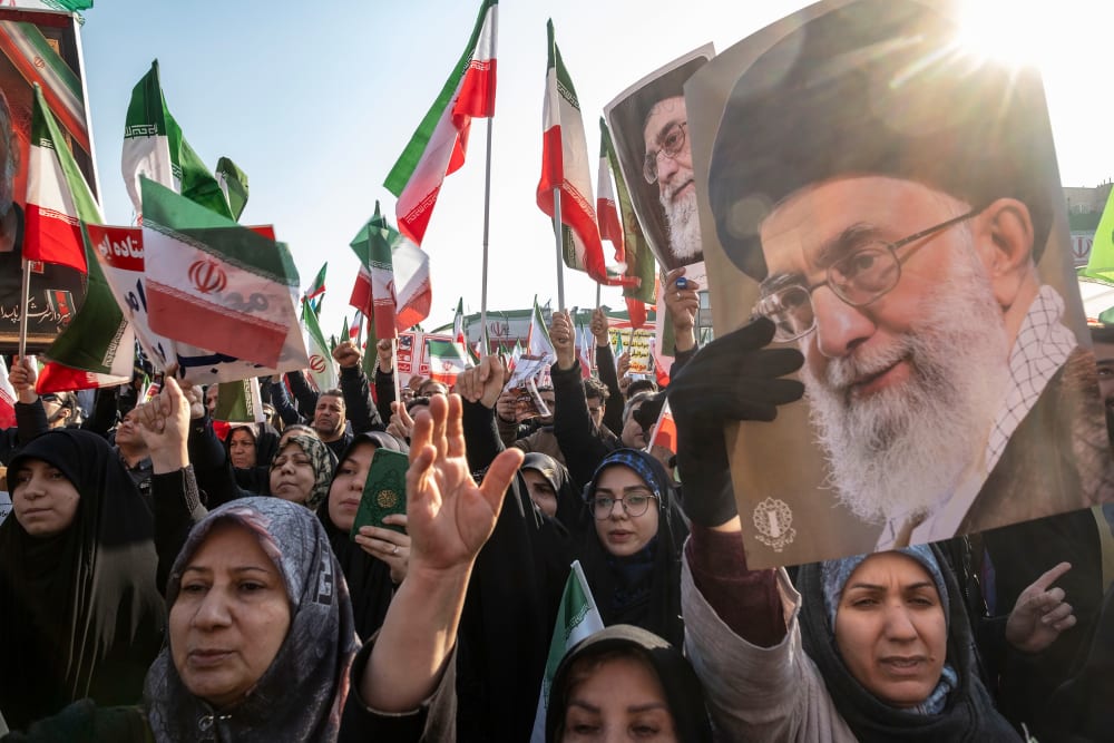 People wave Iranian flags and carry portraits of Ayatollah Ali Khamenei.