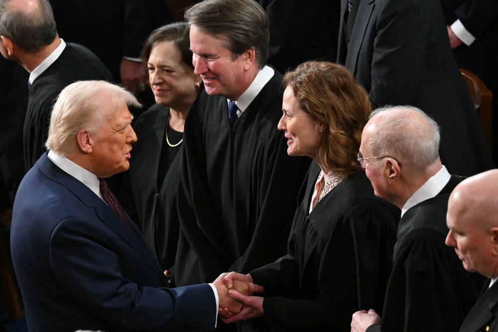 Donald Trump shakes Amy Coney Barrett's hand. They are surrounded by other Supreme Court justices.