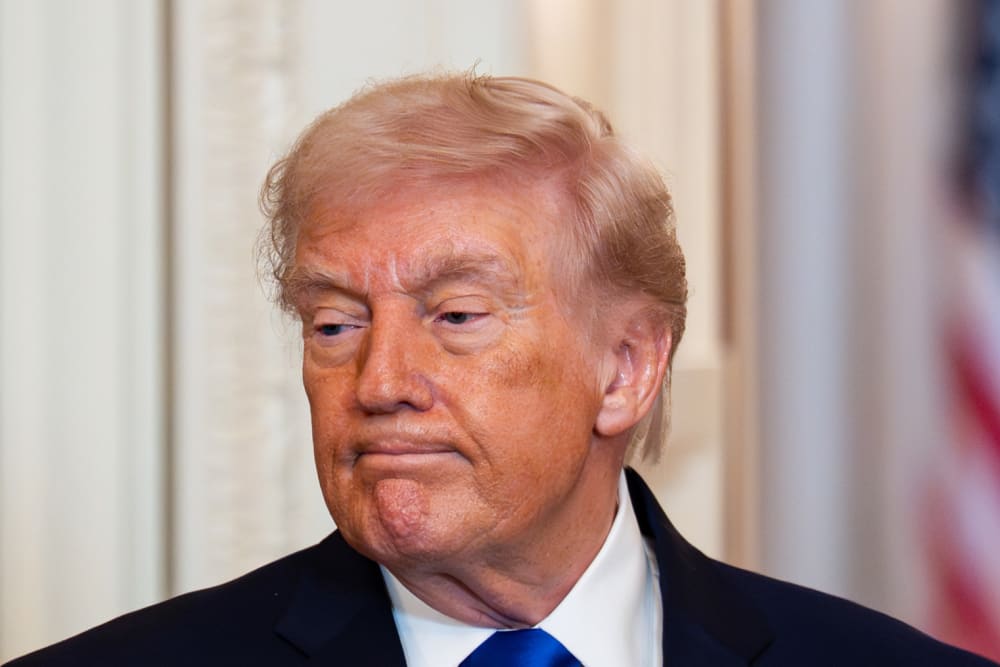 Donald Trump looks down with a negative facial expression.