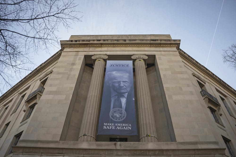 A blue banner with the slogan "Make America Safe Again" and a photo of Donald Trump hangs on the facade of the Department of Justice.