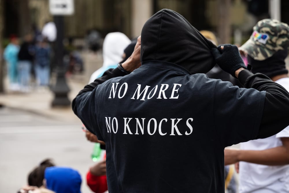 a person is seen from behind as he adjusts his black hoodie.