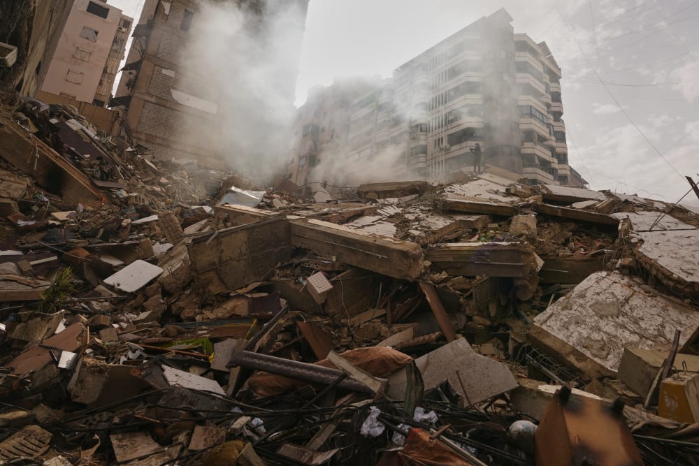 A man stands atop the rubble of a building destroyed in an Israeli airstrike near Beirut