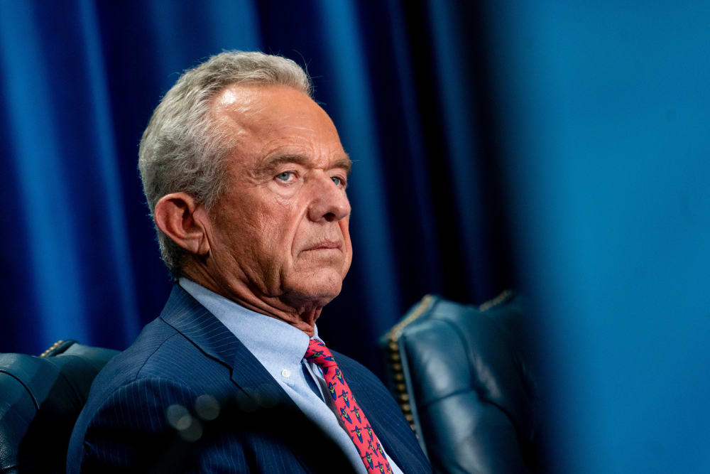 Robert F. Kennedy Jr. sits in a blue leather chair in front of a blue curtain.