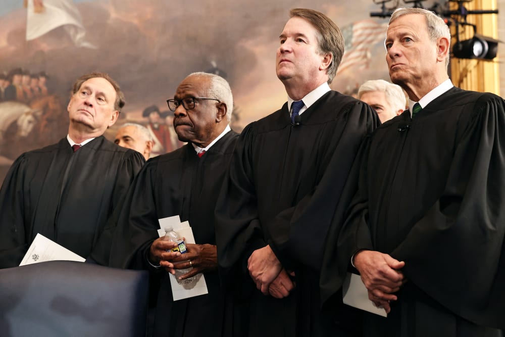 From left to right, Samuel Alito, Clarence Thomas, Brett Kavanaugh and John Roberts stand, dressed in robes.