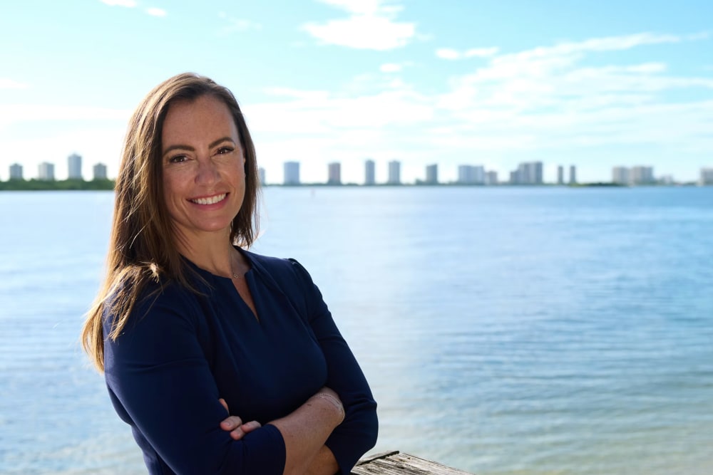 Emily Gregory poses for a photo with her arms crossed in front of a body of water.