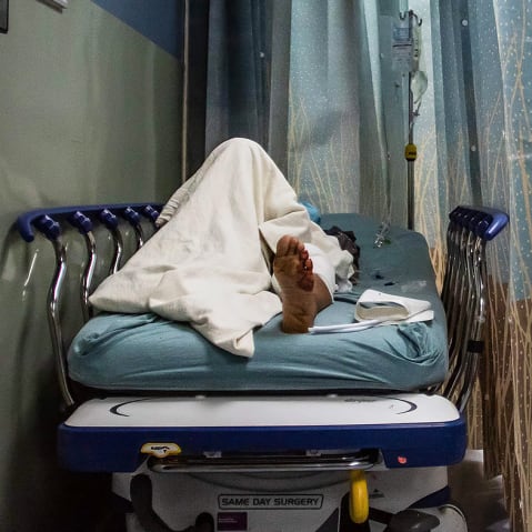 A patient rests in a corridor waiting for a room.