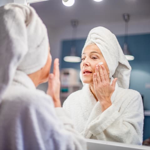 Mature woman applying face cream.