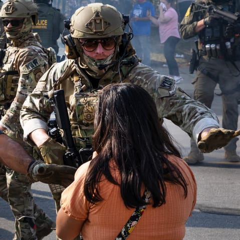 Police take two people into custody, as tear gas fills the air after it was used by federal law enforcement agents in Broadview, IL.