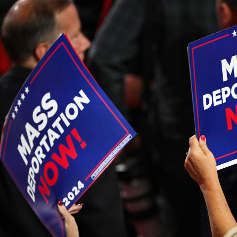 A person holds a sign that reads "Mass Deportation Now" during the third day of the Republican National Convention.
