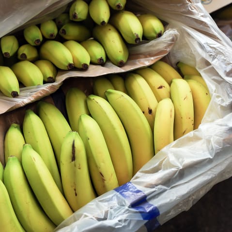 Bananas sit in a box at a fruit and vegetable store.