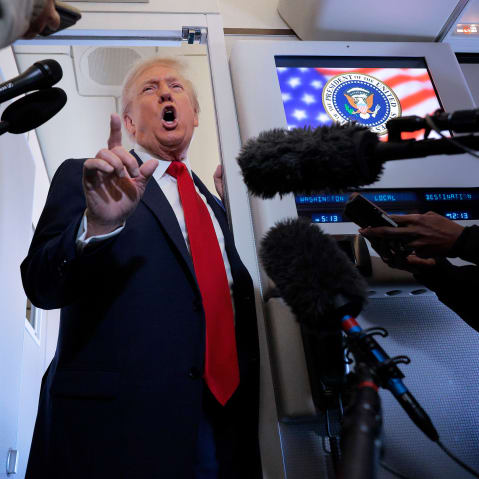 President Donald Trump talks to reporters on board Air Force One.