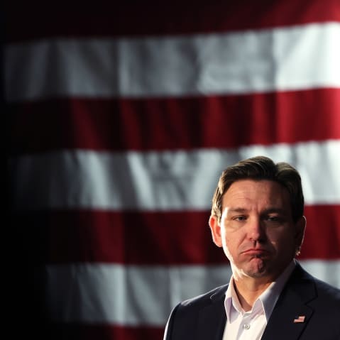 Florida Gov. Ron DeSantis frowning in front of an American flag.