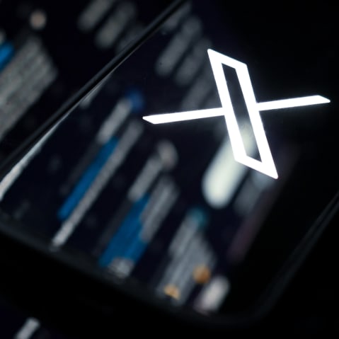 The web version of X mirrored onto a phone showing the X logo.