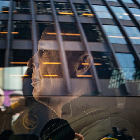 U.S. Border Patrol commander Gregory Bovino sits in the driver's seat surrounded by media and protesters.