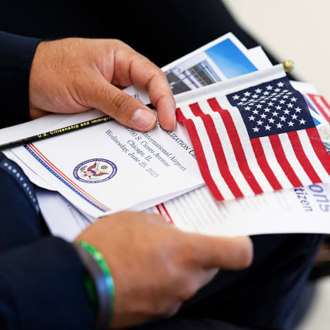 A new US citizen holds a program waiting to take the Oath of Allegiance before receiving their naturalization certificates.