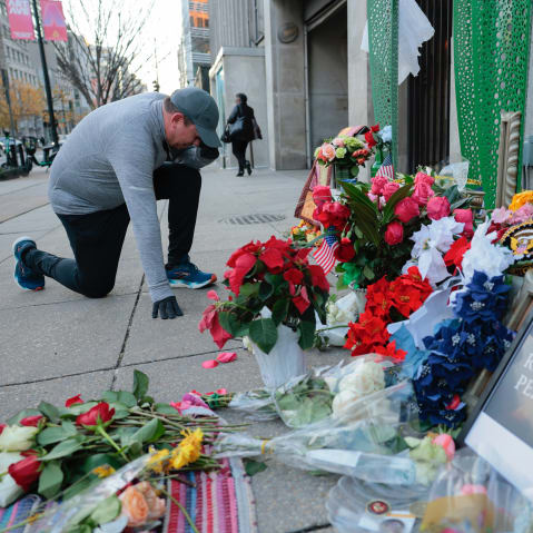 A jogger stops to pray at a makeshift memorial of flowers and American flags outside the Farragut West Metro station on Dec. 1, 2025, in Washington, D.C.