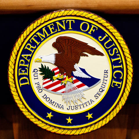 The Department of Justice seal and logo are displayed at the Department of Justice.