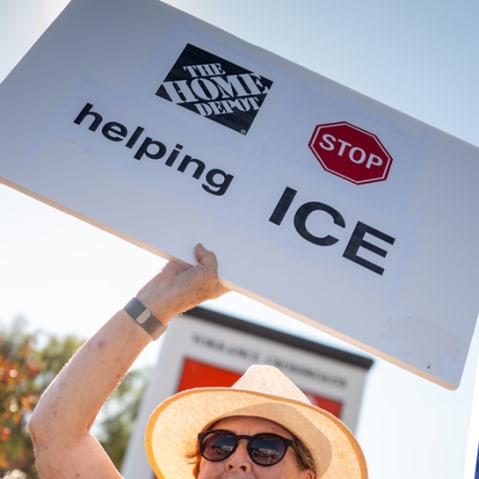 A woman holds a sign that reads "Home Depot Stop Helping ICE" at an anti-ICE and Home Depot protest; Rachel Maddow.