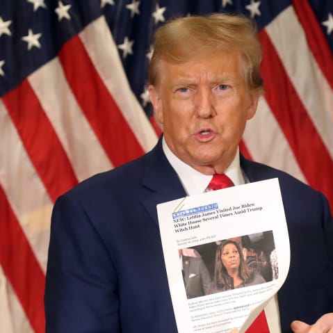 Then former U.S. President Donald Trump holds up a news story about New York Attorney General Letitia James as he speaks to the media at one of his properties at 40 Wall Street following closing arguments at his civil fraud trial on Jan. 11, 2024, in New York City.