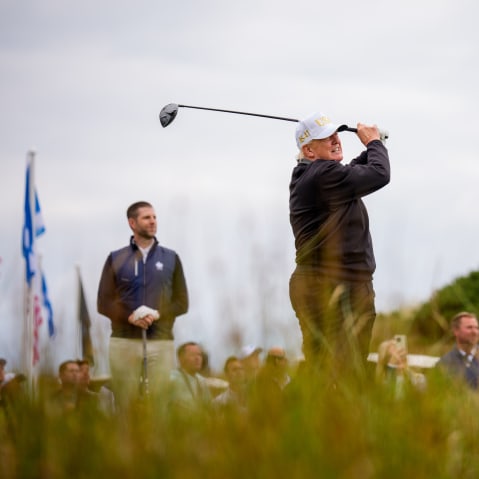 U.S. President Donald Trump, accompanied by his son Eric, left, tees off at a new 18-hole course at Trump International Golf Links on July 29, 2025, in Balmedie, near Aberdeen, Scotland.