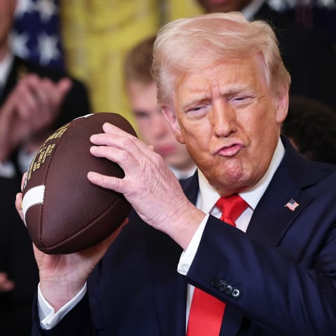 President Donald Trump holds up a football presented to him during a presentation ceremony for the Commander-in-Chief Trophy in the White House on April 15, 2025.
