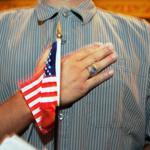 A person holds their hand up to their chest as they swear allegiance to the U.S. flag during a naturalization ceremony in Miami, F.L., on April 28, 2006.