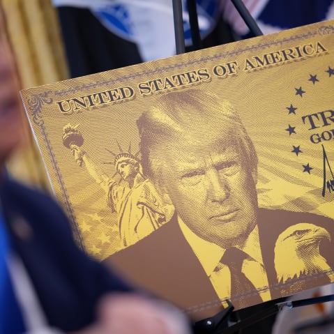 A poster of the “Trump Gold Card” is seen as President Donald Trump delivers remarks