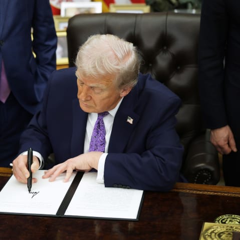 President Donald Trump signs an executive order in the Oval Office.