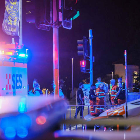 Emergency responders at Sydney’s Bondi Beach confer amid the flashing lights of EMS vehicles.