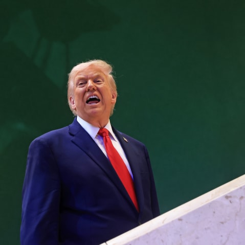Donald Trump against a green wall, with his mouth open.